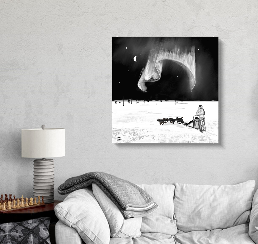 Square black and white illustration of a musher and a husky team crossing a snowy plain under a sweeping silver aurora and a crescent moon, shown on acrylic glass on a grey wall above a white sofa.