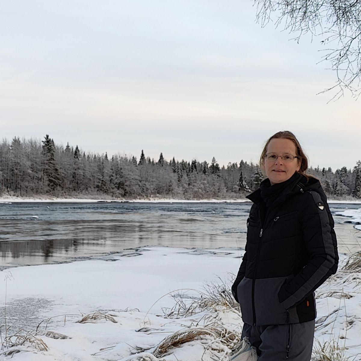 Walking by a fast-flowing river during first snow in Finnish Lapland
