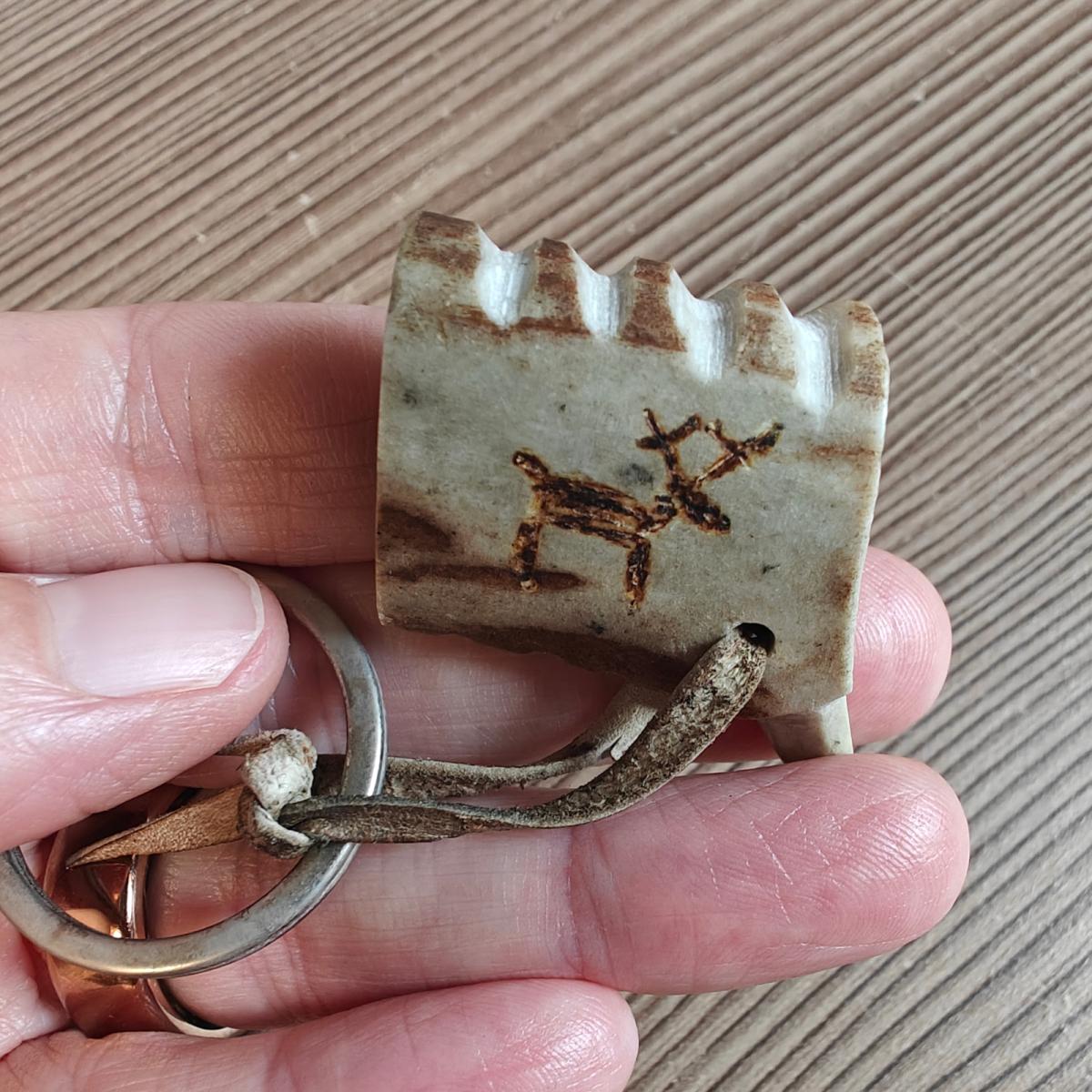 Een hand die een klein rendierfiguurtje vasthoudt, gebrand in een stuk gewei, tijdens een Sámi-verhalenmiddag in Noord-Noorwegen, 2019. Aurealis Creatief.