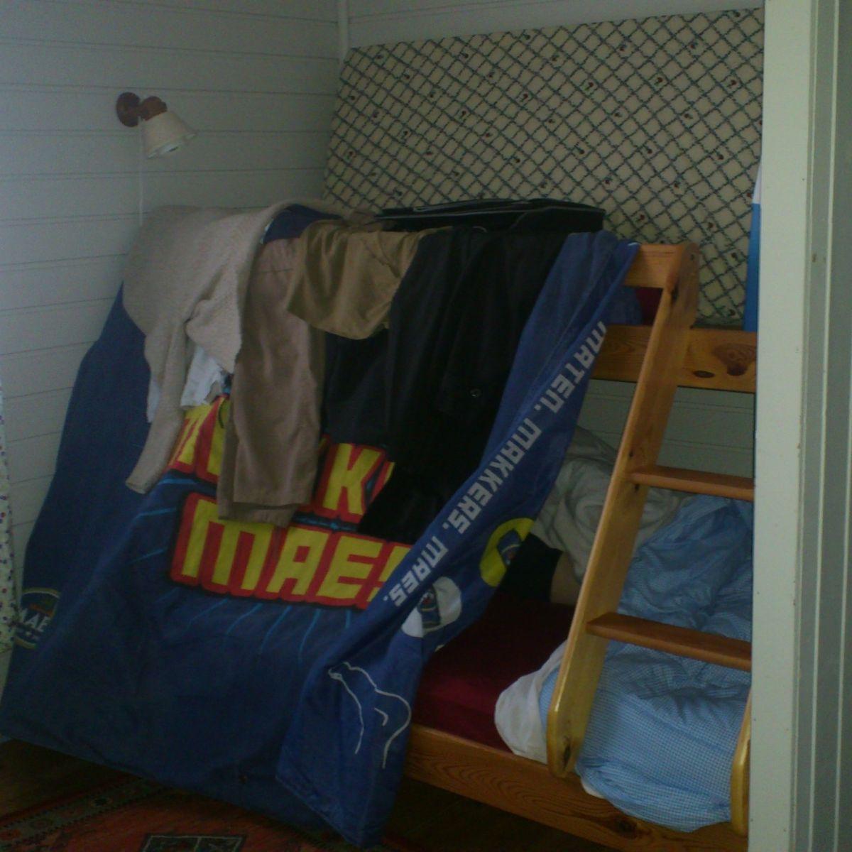 Improvised blackout with a duvet draped over a bunk bed railing in a Norwegian rorbu cabin, to block out the midnight sun while sleeping.